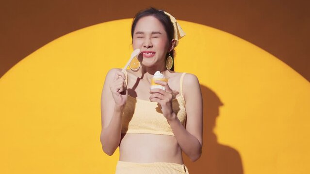 sensitive teeth asian female unhappy feel pain when eat ice cream cold sweet,Young woman with sensitive teeth and cold ice cream on yellow color background