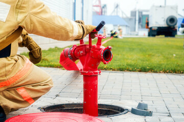 Firefighter sits next to fire hydrant. Back view. Firemen training.