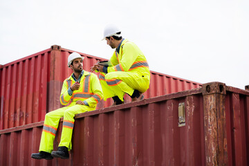 Two worker engineer sitting near a shipping container looks exhausted after working in the work...