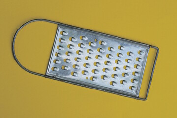 one gray metal grater lies on a yellow table