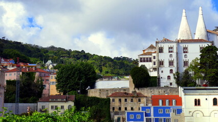 Blick auf Nationalpalast von Sintra bei Lissabon mit großen Küchenschornsteinen neben grünem Wald
