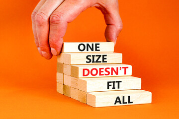 One size does not fit all symbol. Concept words One size does not fit all on wooden blocks. Businessman hand. Beautiful orange background. One size does not fit all business concept. Copy space.