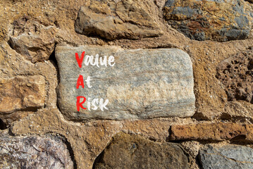 VAR Value at risk symbol. Concept words VAR Value at risk on beautiful big stone in stone wall....