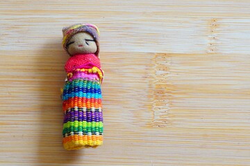 Guatemalan worry doll or quitapenas on wooden background