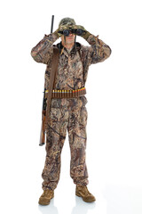 Full length portrait of a mature hunter with a shotgun looks through binoculars to the side, isolated on white background. Duck hunter with a rifle on his shoulder posing in studio.