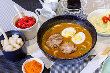 Japanese curry with udon noodle and crispy pork chop croquettes and boiled egg topping on bowl cup style.