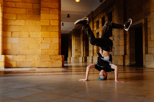 white teenage boy breakdancing in the arcade of an old building. b-boy. youth culture.
