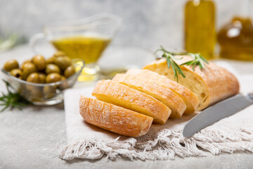 Ciabattas, olive oil in a bowl with olives, herbs, spices, garlic, pesto, parmesan and ciabatta bread on a texture background.Banner. Healthy food concept.Delicacy. Mediterranean Kitchen. Copy space.