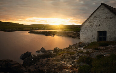 Magical sunrise scenery of fisherman's hut by the lake with mountains in the background at Screebe, connemara national Park in County Galway, Ireland 