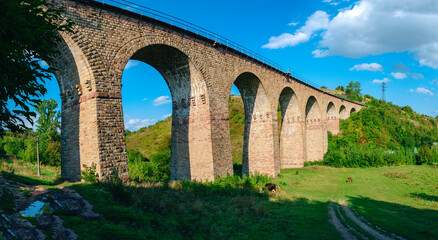 Obraz premium Stone railway ancient arch bridge over the green valley
