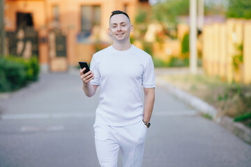 Stylish man in white costume walking at the street with mobile phone