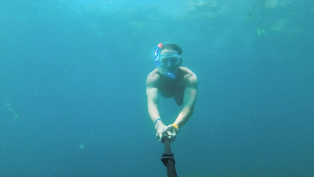 Shot of a man swimming underwater wearing a mask with a breathing tube and taking a selfie while relaxing on a sunny day at sea
