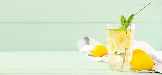 Glass of tasty iced tea with lemon on green wooden background with space for text
