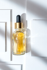glass cosmetic dropper bottle with blank label on white layered podium background with gobo...