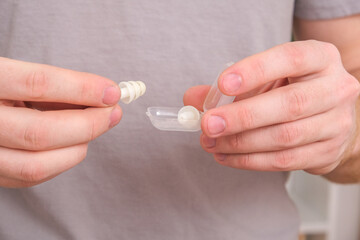 A man inserts earplugs in his ears so as not to hear extraneous noise, music, snoring. Silicone earplugs for sleeping.