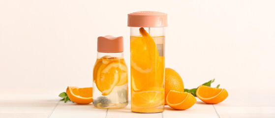 Bottles of orange infused water on white background