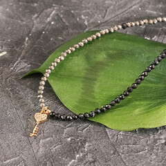 seed beads chocker necklace with key pendant on grey background. 