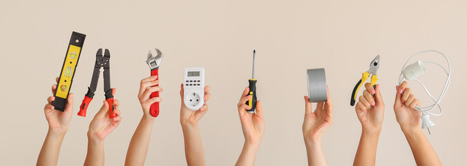 Female hands with set of electrician's supplies on light background