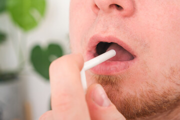 Naklejka premium An adult male uses a throat spray to relieve sore throat. The concept of medicine, health.