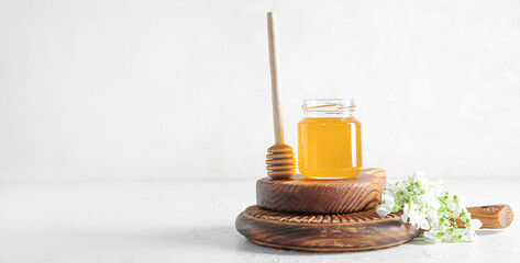 Jar of honey, flowers of acacia and dipper on light background with space for text