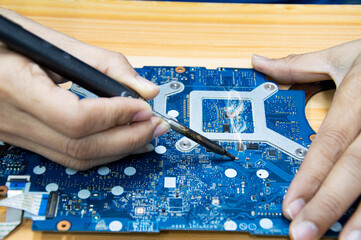 Motherboard repair. Motherboard, solder parts, male, close-up.