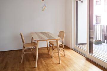 Wooden dining table with wicker chairs in light room