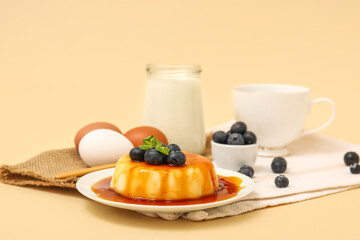 Plate with delicious pudding, blueberries and mint covered by caramel syrup on beige background