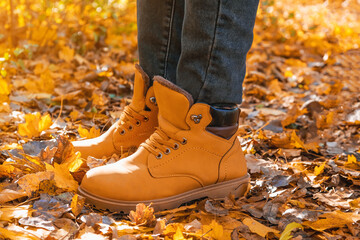 A man in red shoes walks through the autumn forest. Orange shoes on yellow dry fallen leaves. Rest, relaxation in the autumn forest. Autumn concept of walking through forest. Recreation and travel.