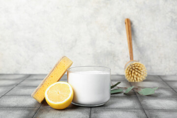 Obraz na płótnie Canvas Bowl of baking soda, cleaning sponge, brush and lemon on grunge tile table