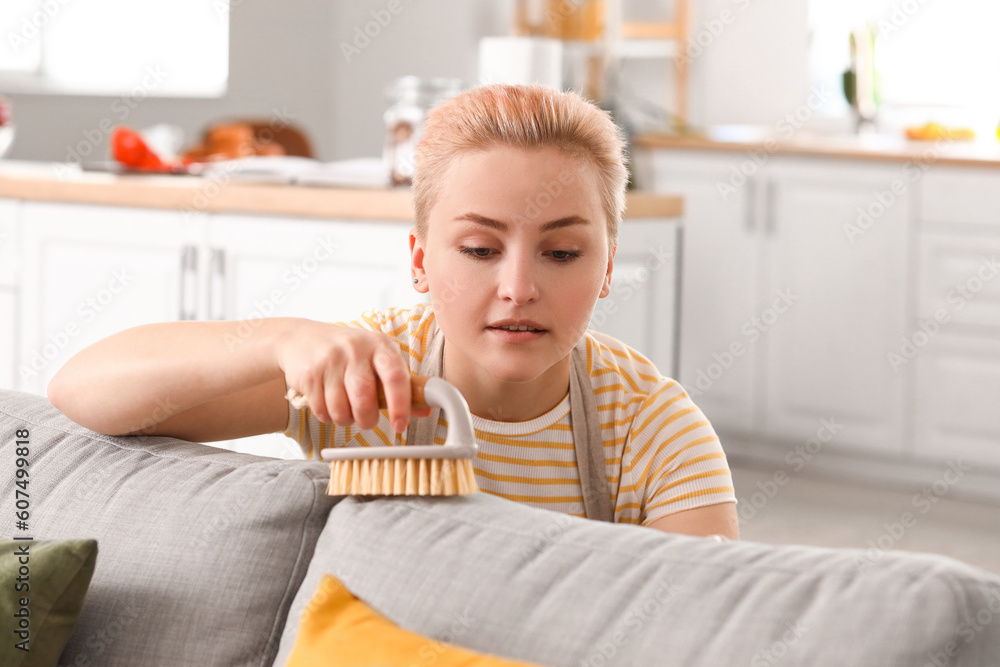 Canvas Prints Young woman cleaning sofa with brush at home