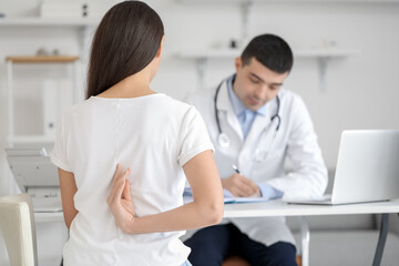 Young woman with bad posture visiting doctor in clinic, back view