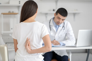 Obraz premium Young woman with bad posture visiting doctor in clinic, back view