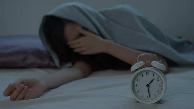 asian woman in bed late trying to sleep suffering insomnia, sleepless or scared in a nightmare, looking sad worried and stressed. Tired and headache or migraine waking up in the middle of the night.