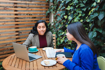 Secure Your Future: Latina Insurance Saleswoman Presenting Life Insurance Options to a Customer in a Cafe