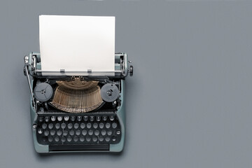Vintage typewriter with blank paper sheet on grey background