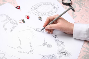 Female jeweler drawing adornment on grunge table, closeup