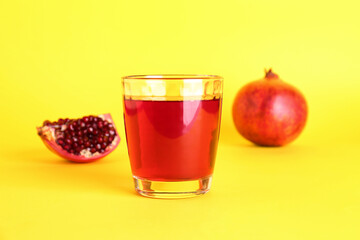 Glass of fresh pomegranate juice on yellow background