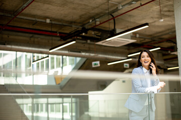 Young business woman using mobile phone in the office hallway