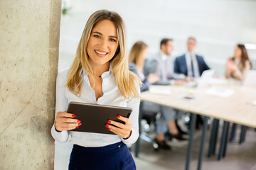 Young business woman with digital tablet in the office hallway