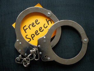 A sheet with an inscription Free speech and handcuffs on it.