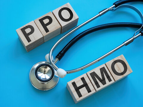 Wooden cubes with letters PPO and HMO near a stethoscope.