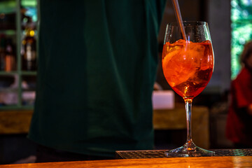 Realistic photo, close-up view of professional bartender in bar making cocktail in a tall glass, with ice and alcohol, male hands in picture