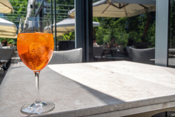 Girl drink iced alcohol Aperol spritz cocktail on summer terrace, in cafe or restaurant