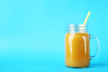 Orange smoothie in glass jar on blue background