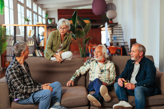 Four senior people having conversation while resting in living room