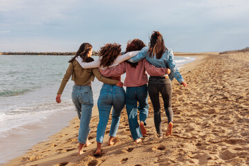 Rare view of four young women walking together on beach