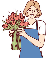 Positive woman flower seller stands with luxurious bouquet and smiling looks at camera