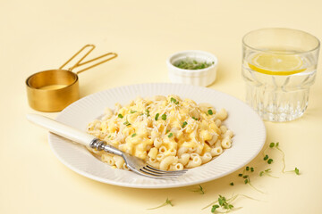 Plate of tasty Italian pasta with Cheddar cheese on yellow background