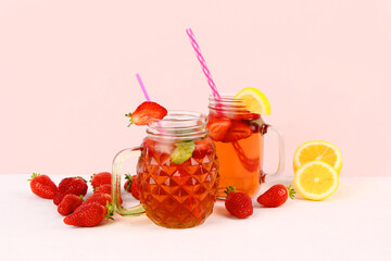 Mason jars of tasty strawberry drink on white background