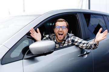 Man customer sitting in car salon and smiling, choosing auto and wanting to buy new automobile in...